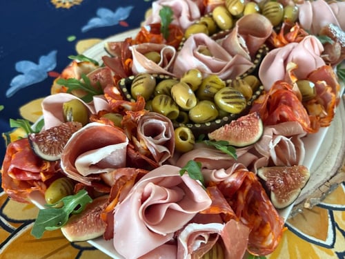 Elegant charcuterie board with olives, folded meats, and figs.