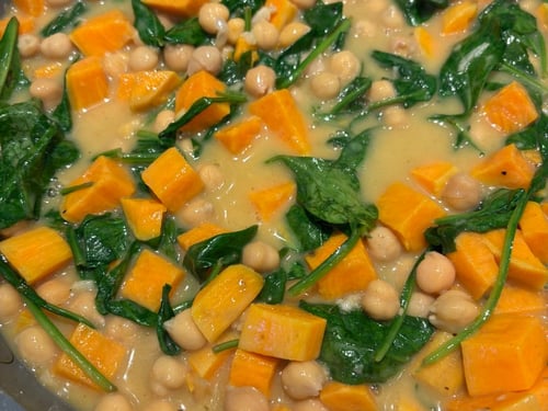Close-up of sweet potato, chickpea, and spinach curry in a pan.