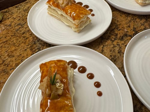 Plated Mille-Feuille dessert with caramel glaze and delicate crispy garnish.