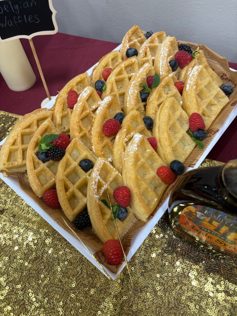 Platter of Belgian waffles with fresh berries and powdered sugar.