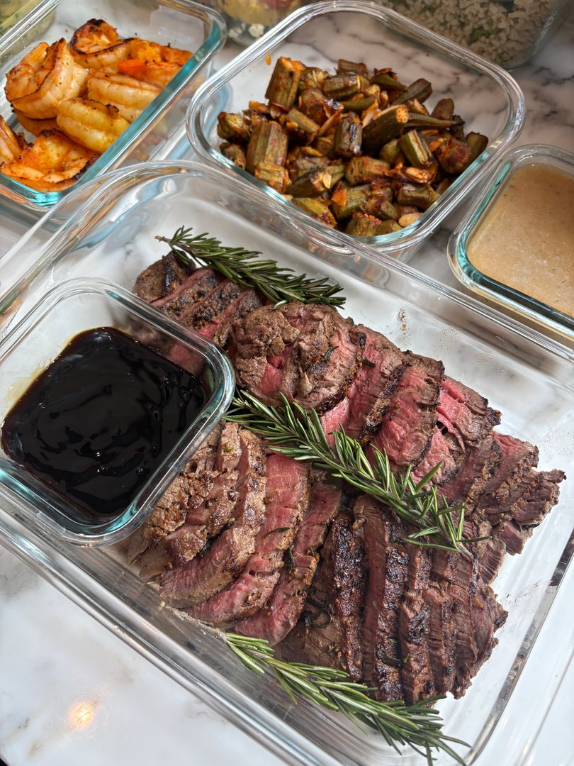 Sliced steak with rosemary and a side of dark sauce.