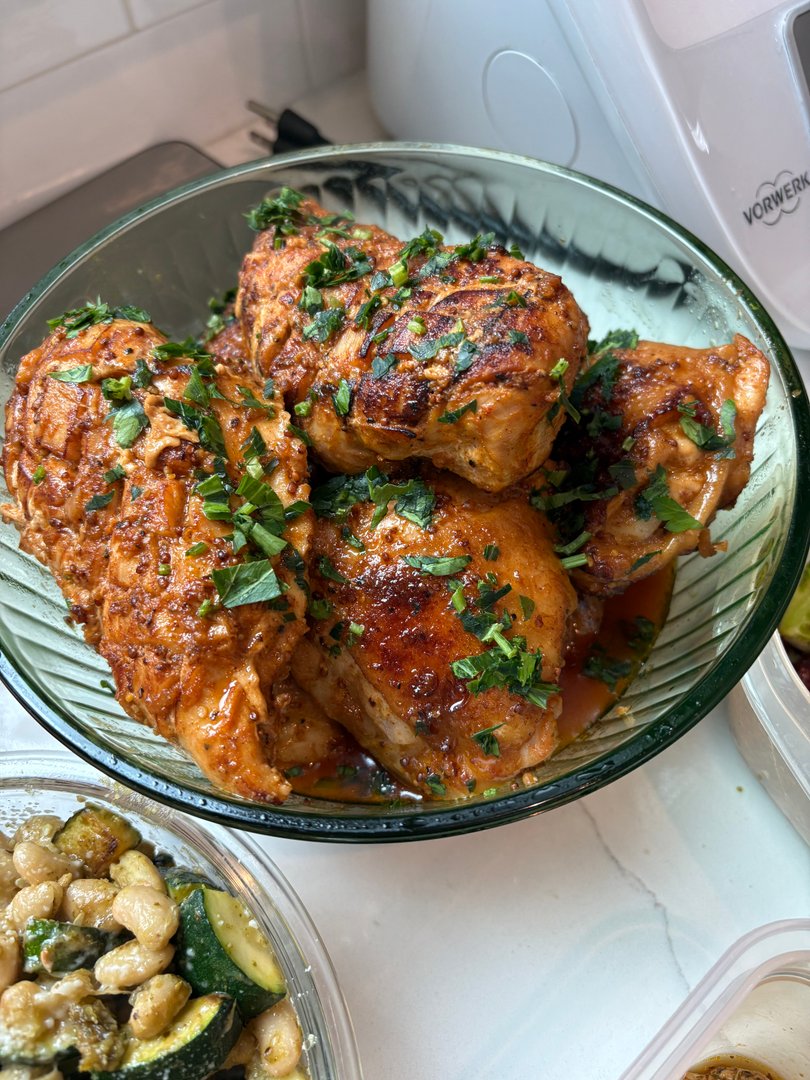 Glazed chicken pieces garnished with fresh parsley in a glass bowl.
