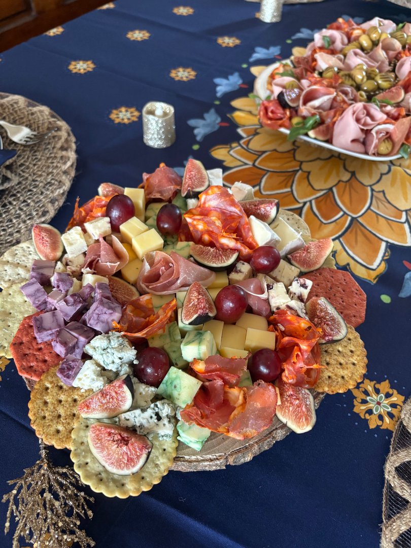 Rustic charcuterie board with cheeses, meats, figs, and grapes.