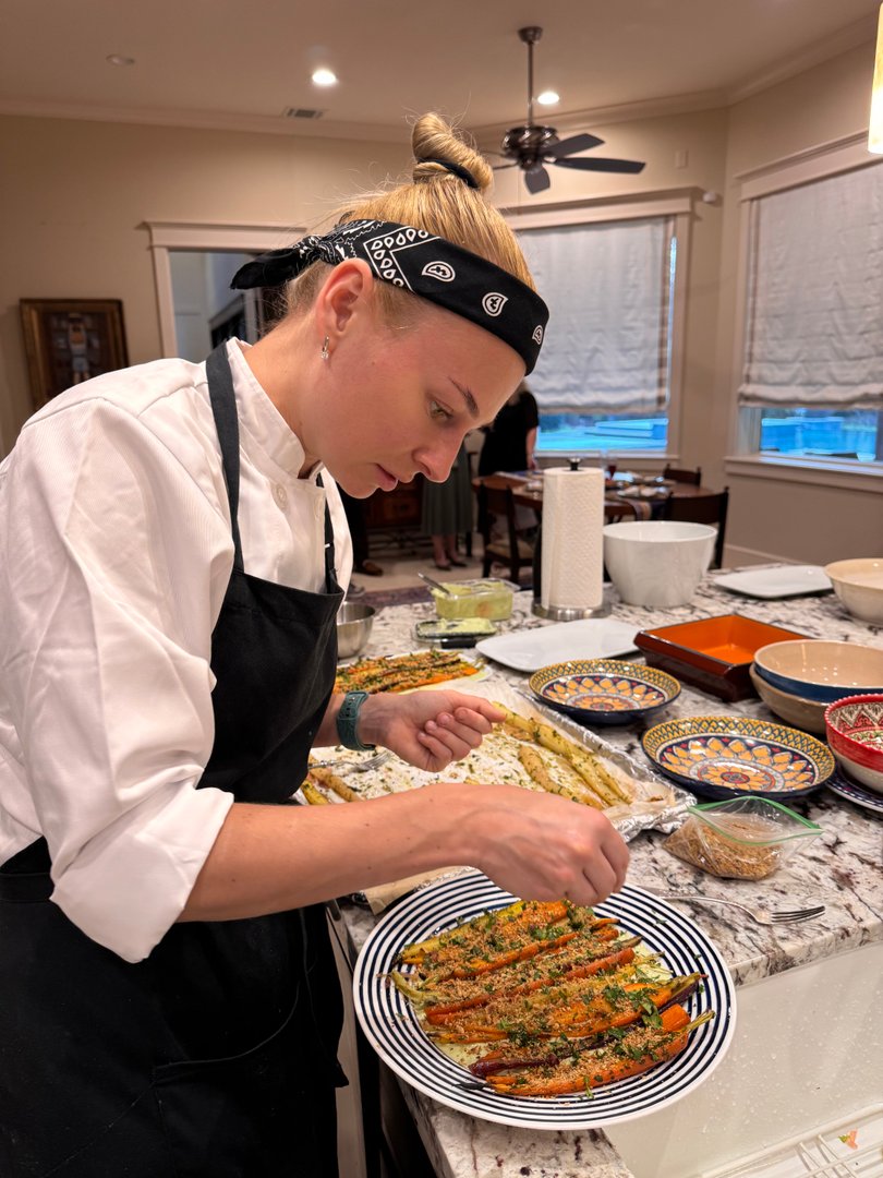 Chef Ana garnishing roasted carrots with hazelnut dukkah.