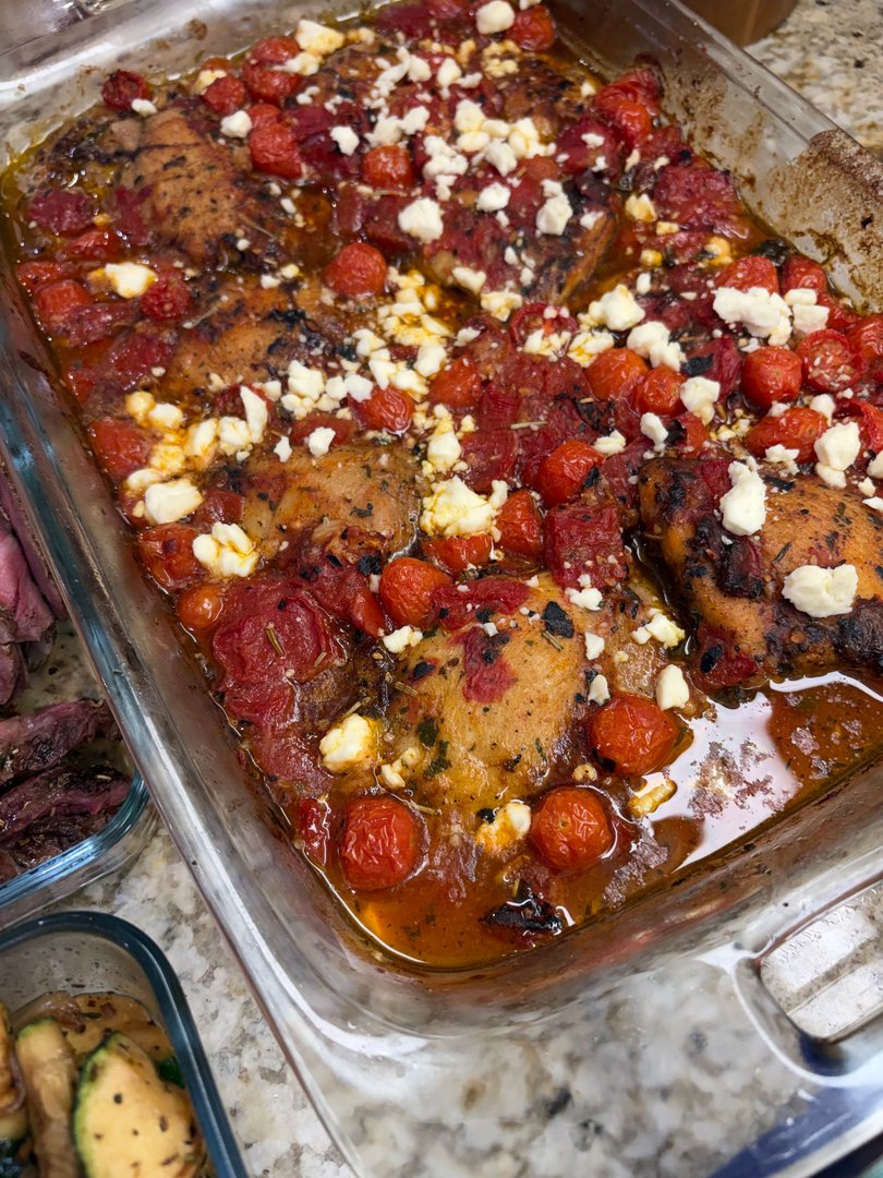 Baked chicken thighs with cherry tomatoes and crumbled feta cheese.