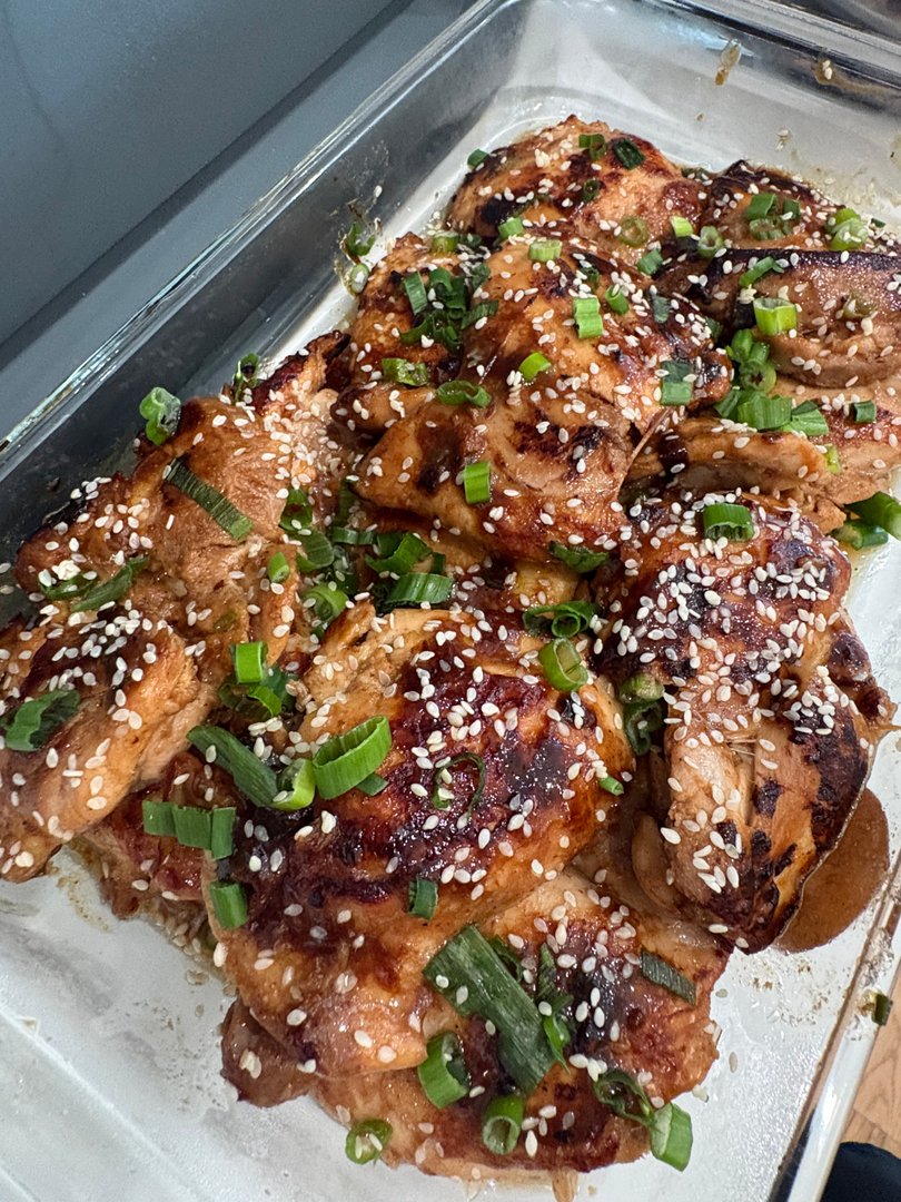 Sesame chicken thighs garnished with green onions in a baking dish.