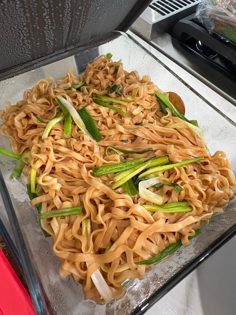 Garlic noodles with sliced green onions in a clear dish.