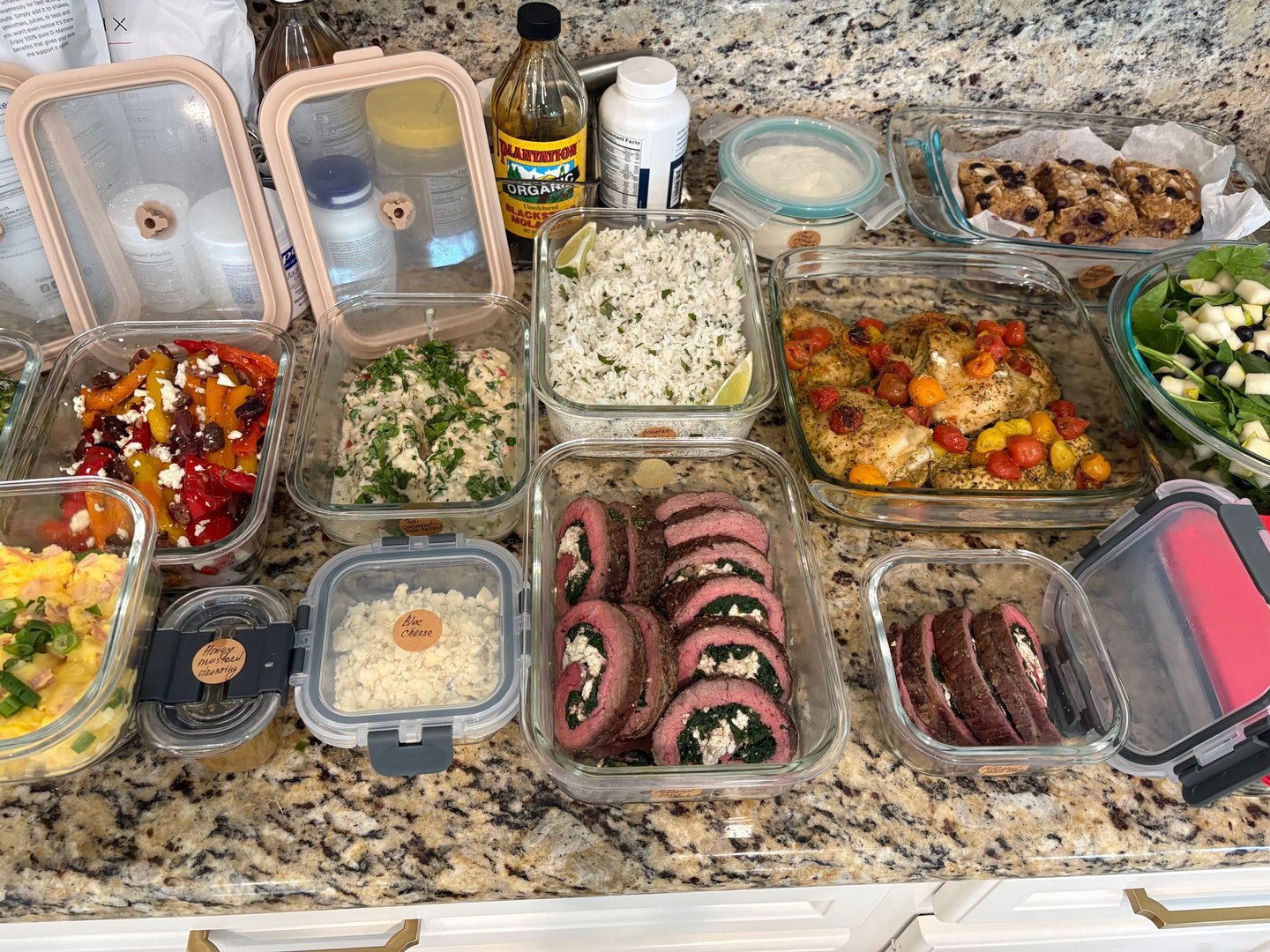 Full spread of meal prep containers with various dishes and supplements.