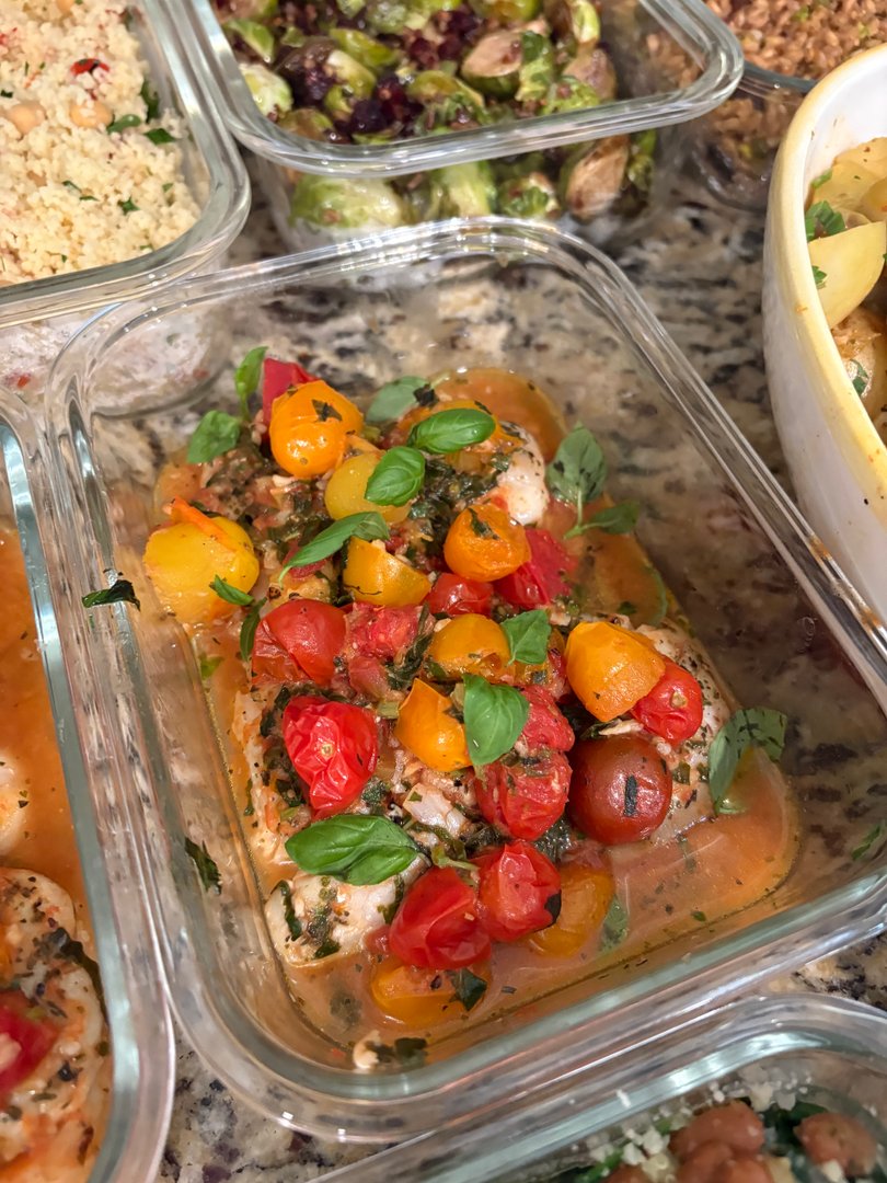 Close-up of chicken with blistered cherry tomatoes and fresh basil.