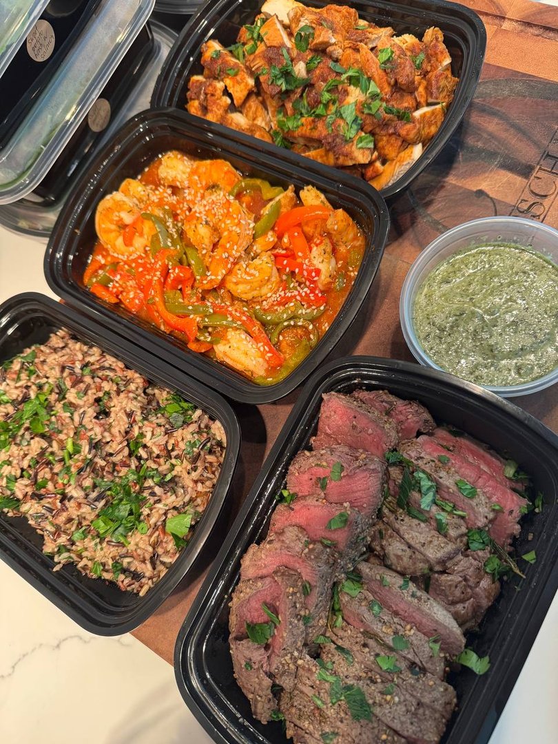 Assortment of prepared meals: chicken, shrimp, steak, rice, and pesto