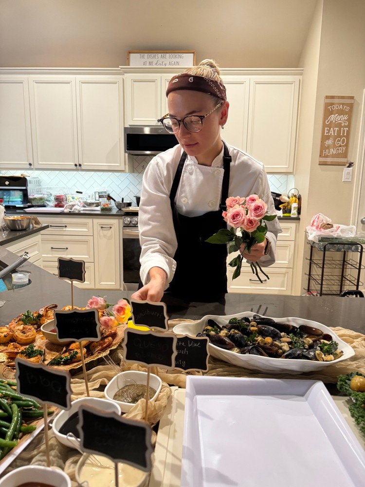 Chef Ana arranging flowers on a buffet table with various dishes