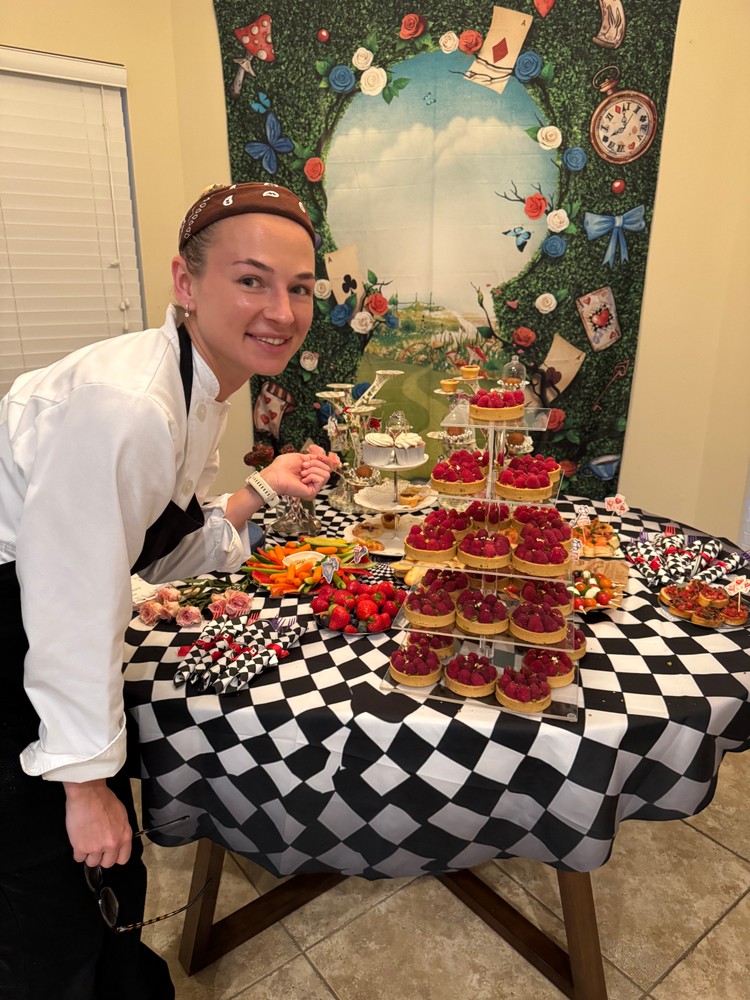 Chef Ana proudly presenting a dessert table with raspberry tarts and skewers