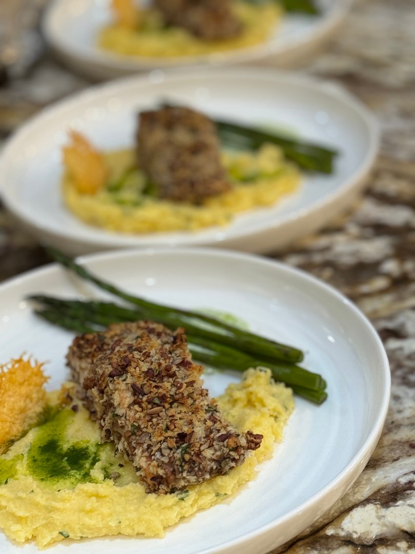 Close-up of pecan-crusted fish with polenta, asparagus, and green herb oil.
