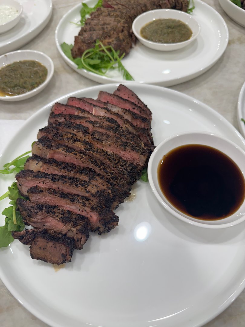 Sliced coffee-crusted ribeye steak with a savory dipping sauce.
