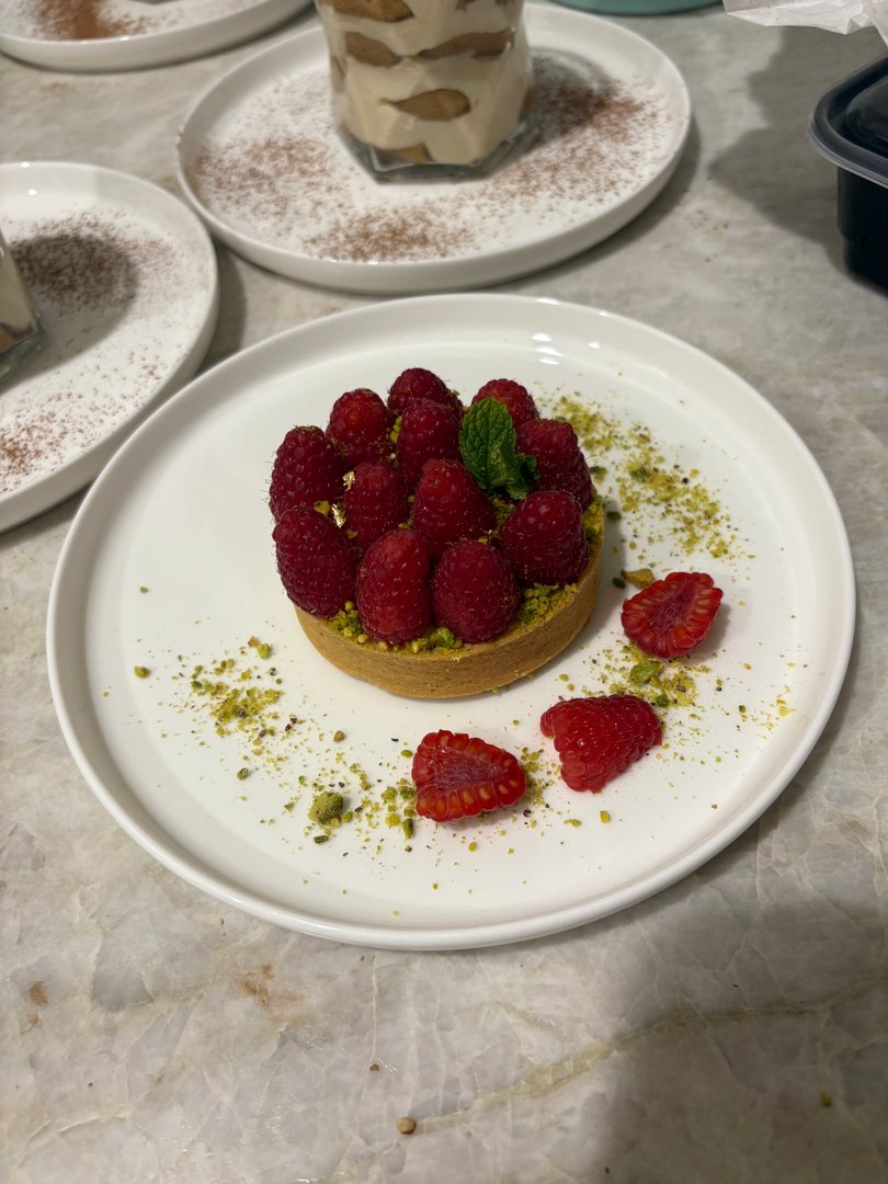 Raspberry tart with pistachios and a mint garnish.